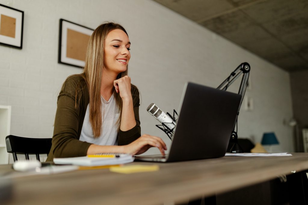 Woman smiling while working on laptop at home.